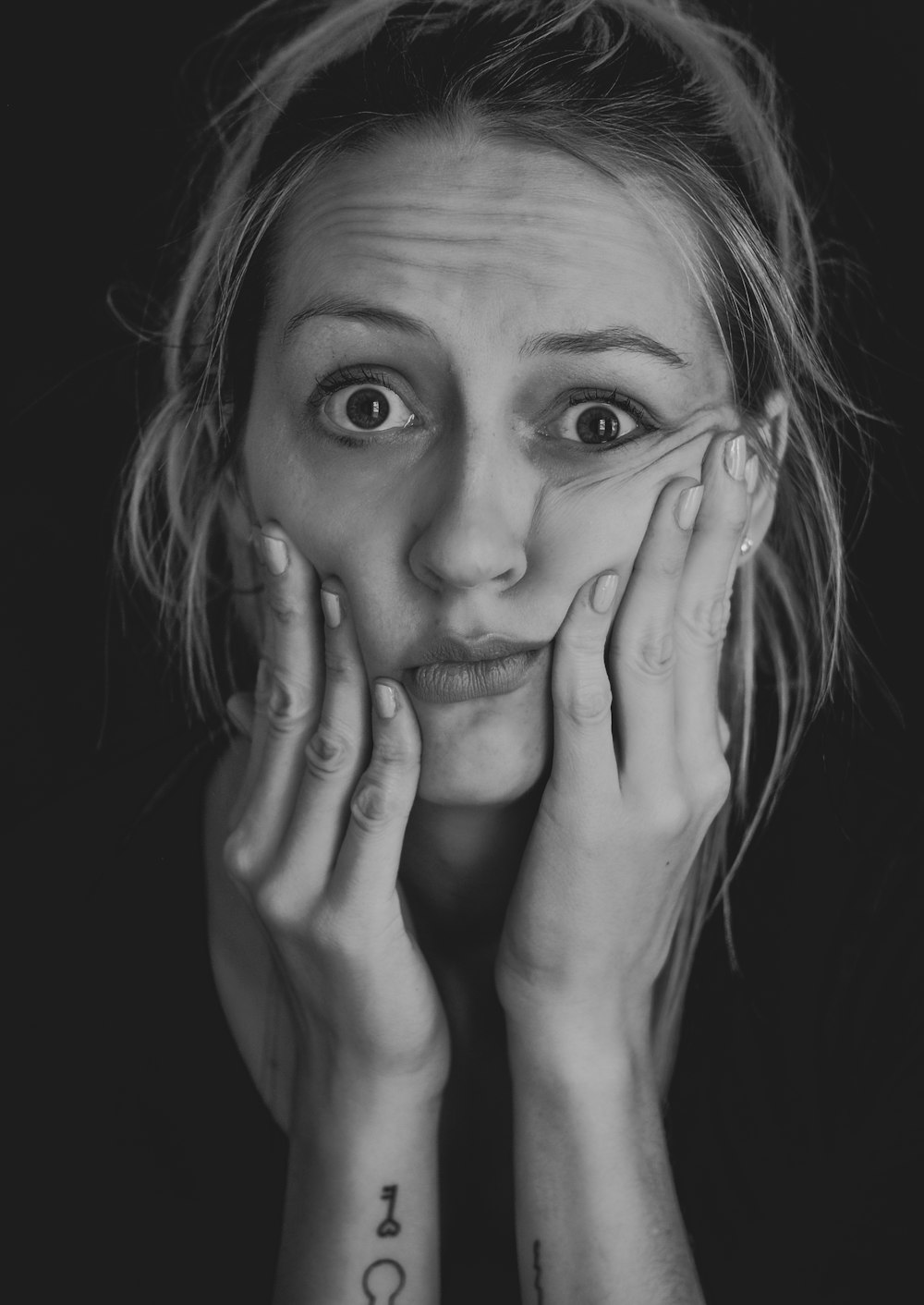 Foto in scala di grigi di donna che si copre il viso con la mano