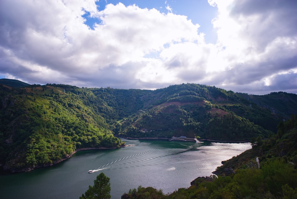 Montañas verdes cerca del cuerpo de agua bajo nubes blancas durante el día