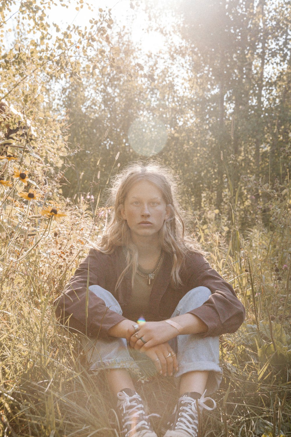 woman in gray long sleeve shirt sitting on brown grass field during daytime