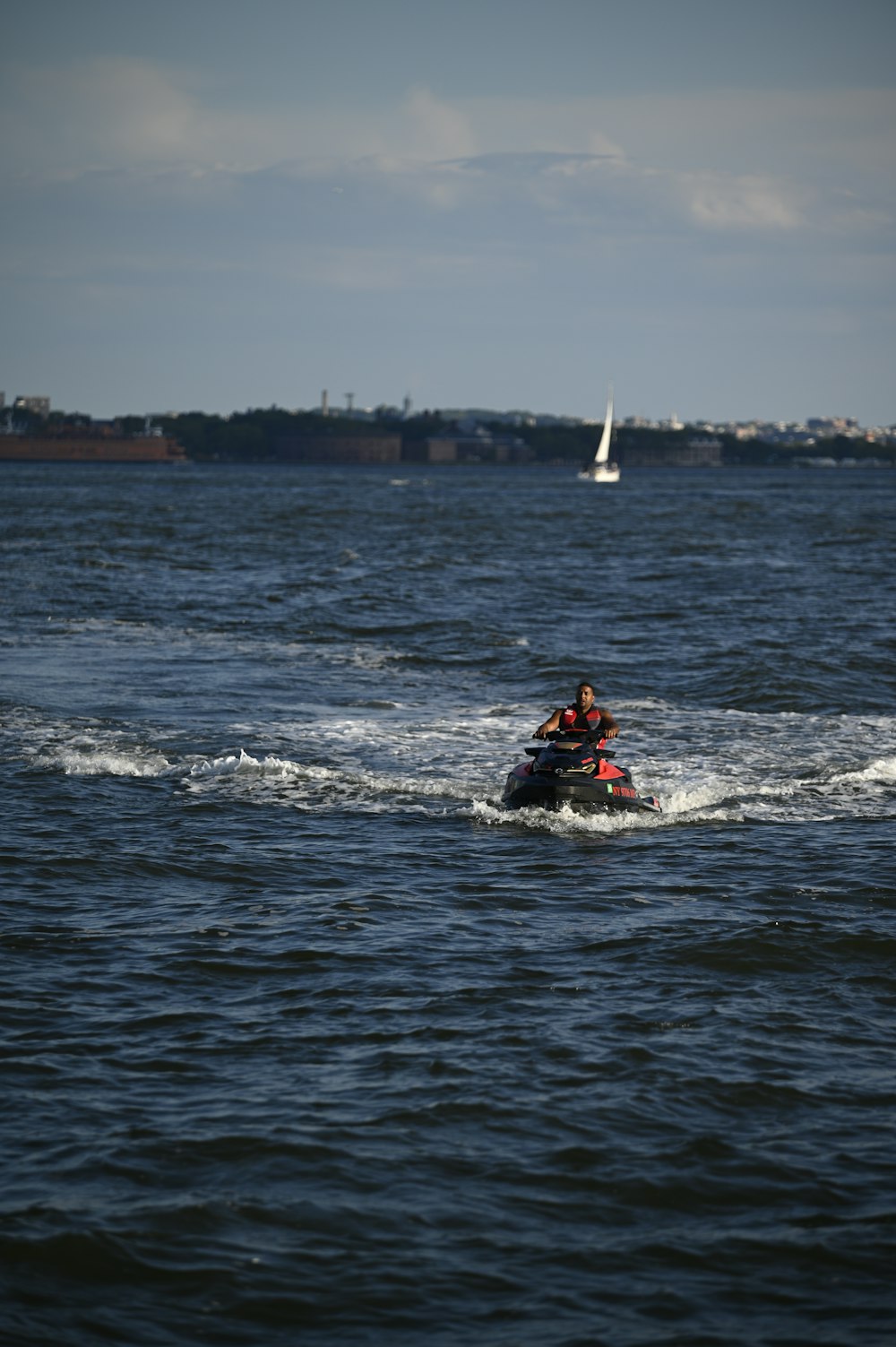 Uomo in giubbotto rosso e nero che cavalca sul kayak rosso in mare durante il giorno