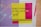 A bold and colorful poster features the phrase 'Build Confidence in the Creative Spirit' in black and yellow text. The background displays vibrant vertical stripes in blue and pink, with contrasting designs in yellow and purple.