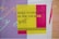 A bold and colorful poster features the phrase 'Build Confidence in the Creative Spirit' in black and yellow text. The background displays vibrant vertical stripes in blue and pink, with contrasting designs in yellow and purple.