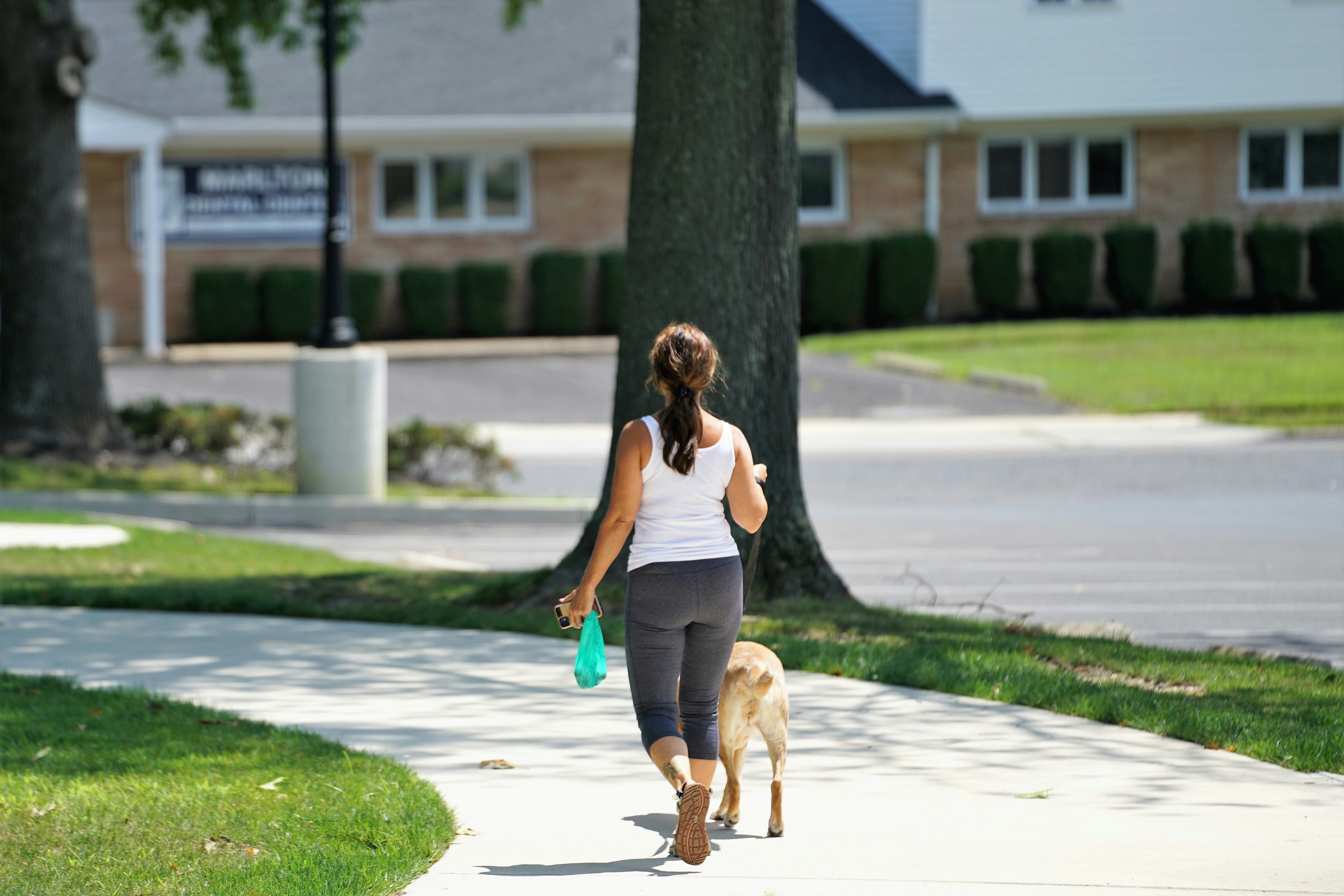 woman in gray tank top and blue denim shorts running on gray concrete road during daytime