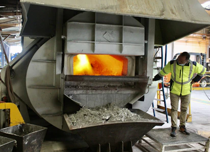 Close-up of skilled technician inspecting refractory materials near a furnace.