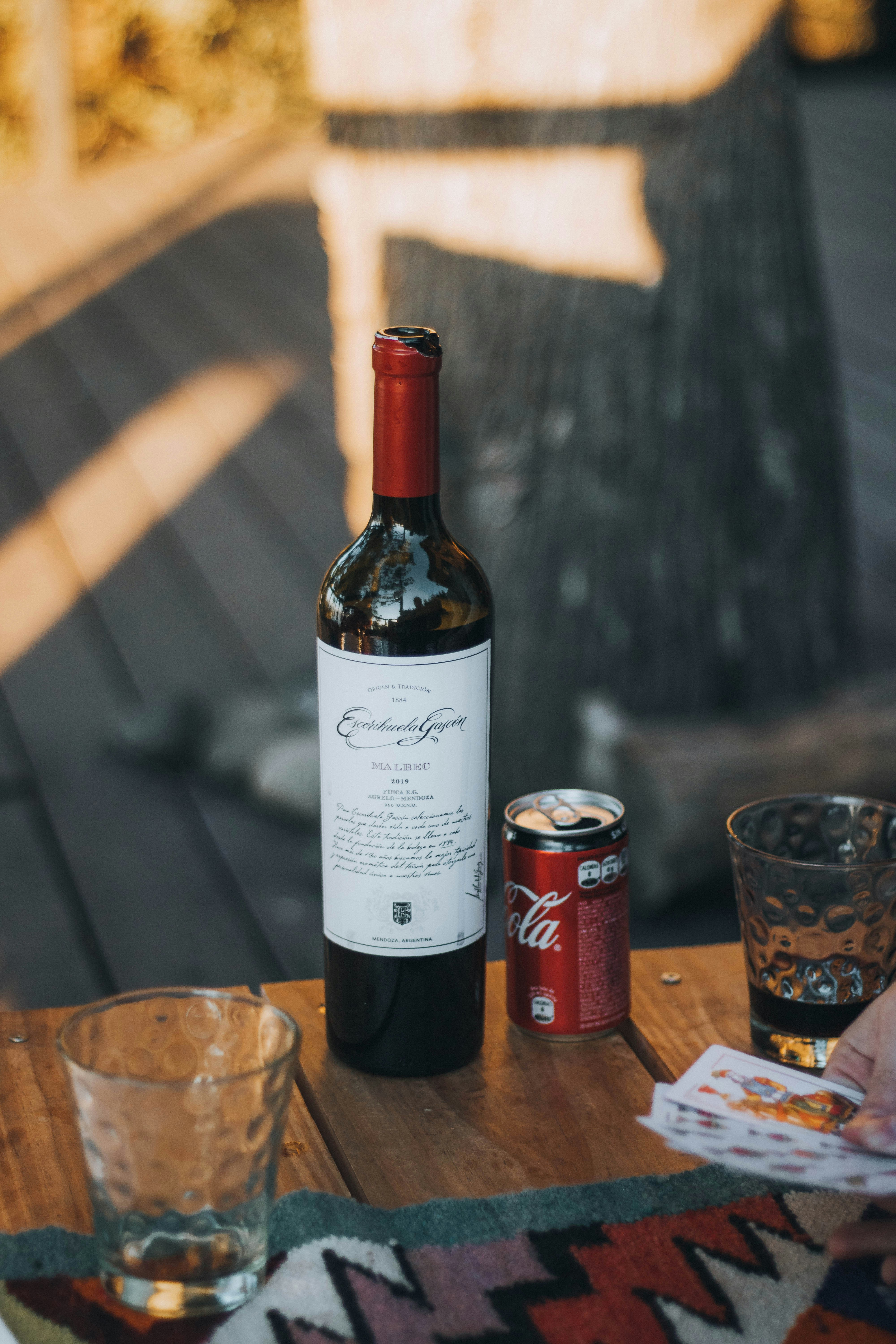 white labeled bottle beside clear drinking glass on brown wooden table