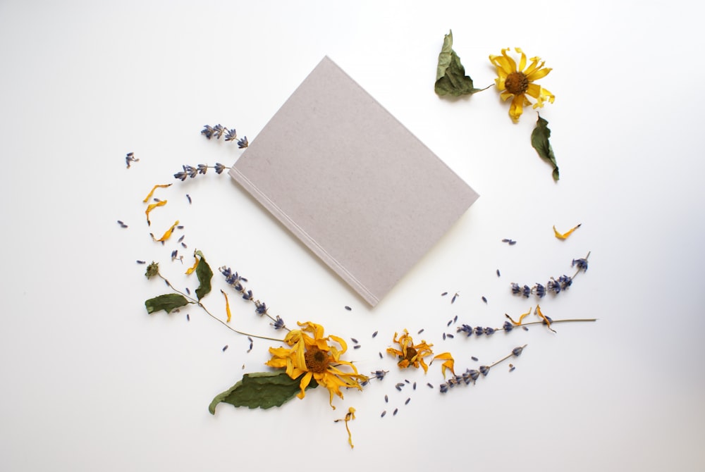 yellow flowers beside gray book