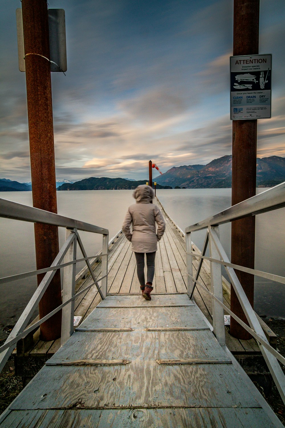 woman in white long sleeve dress walking on wooden dock during daytime