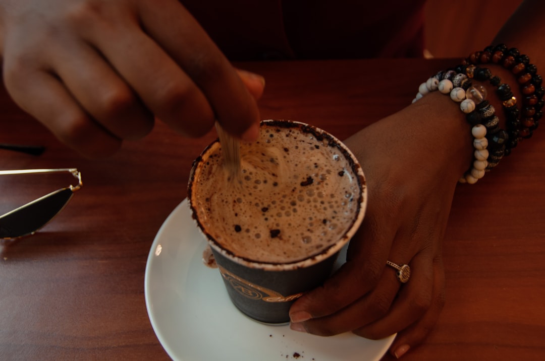 person holding white ceramic mug with brown liquid