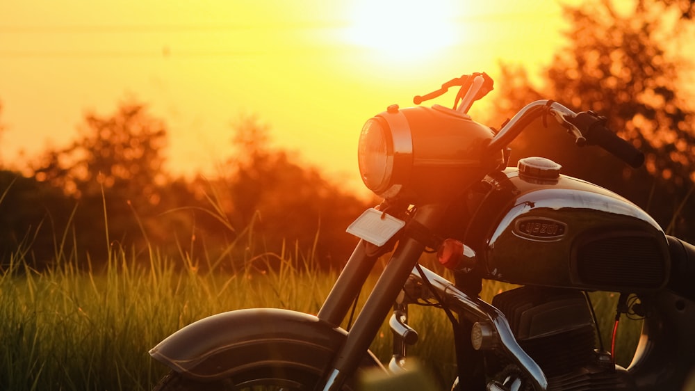 red motorcycle on green grass field during sunset