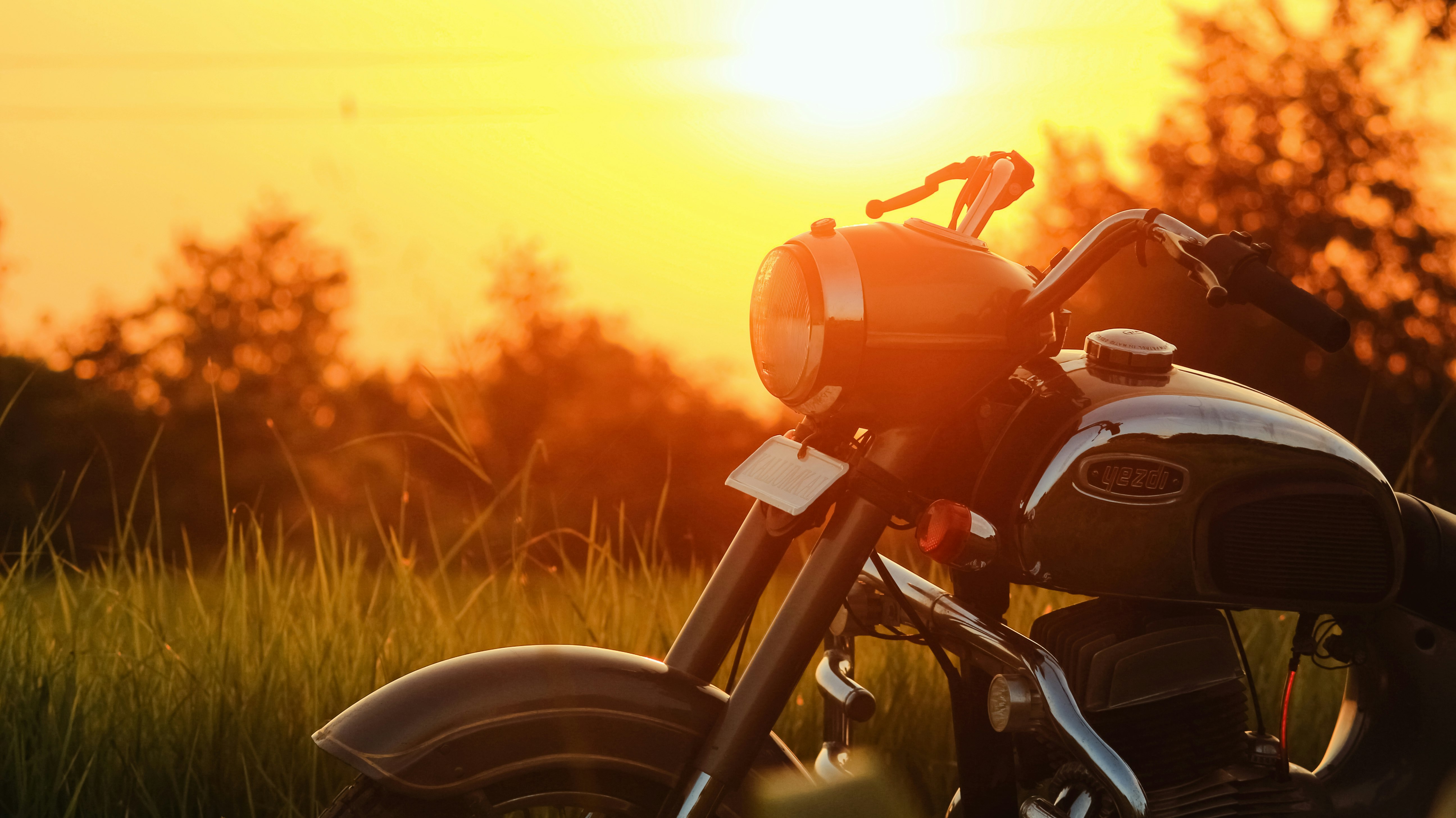 red motorcycle on green grass field during sunset