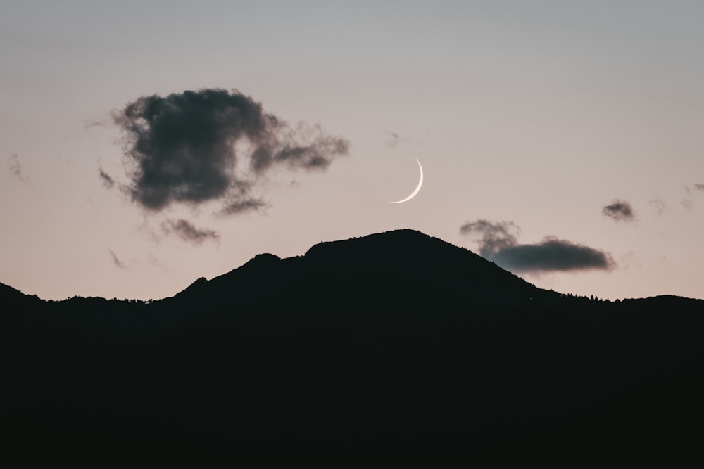 silhouette of mountain under white clouds during night time