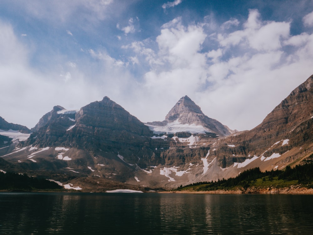 snow covered mountain near body of water during daytime