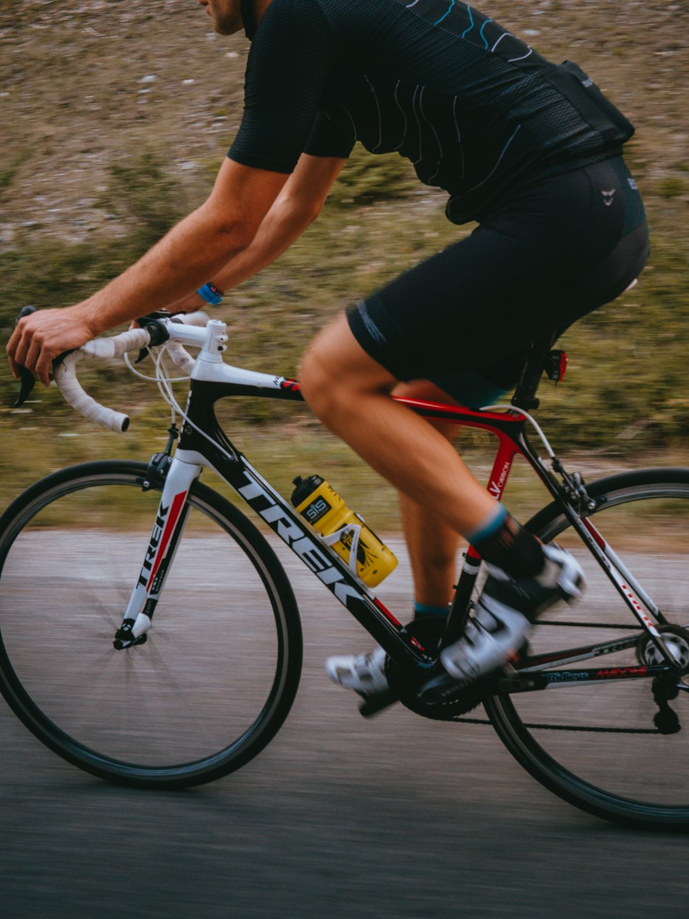 Uomo in maglietta nera e pantaloncini arancioni in sella alla mountain bike in bianco e nero