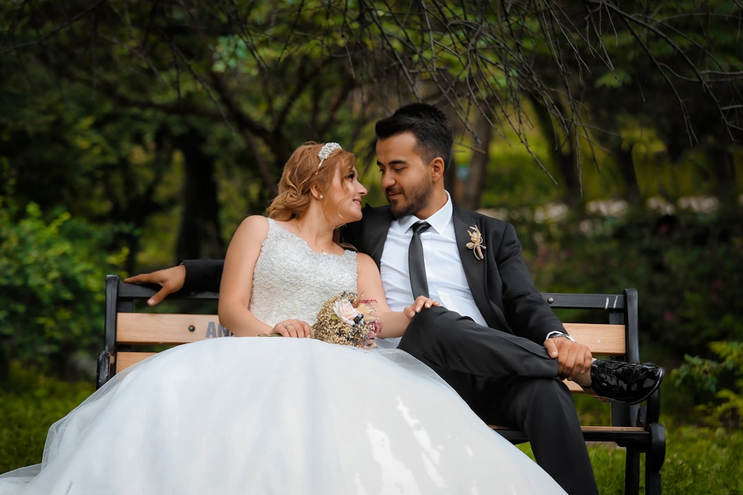 bride and groom sitting on brown wooden bench