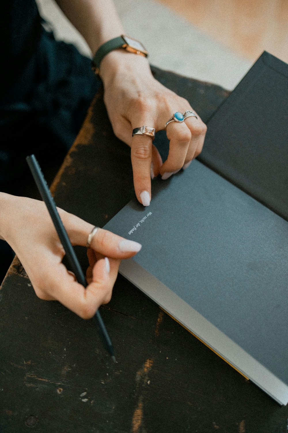 Person mit schwarzem Stift Schriftzug auf blauem Tisch