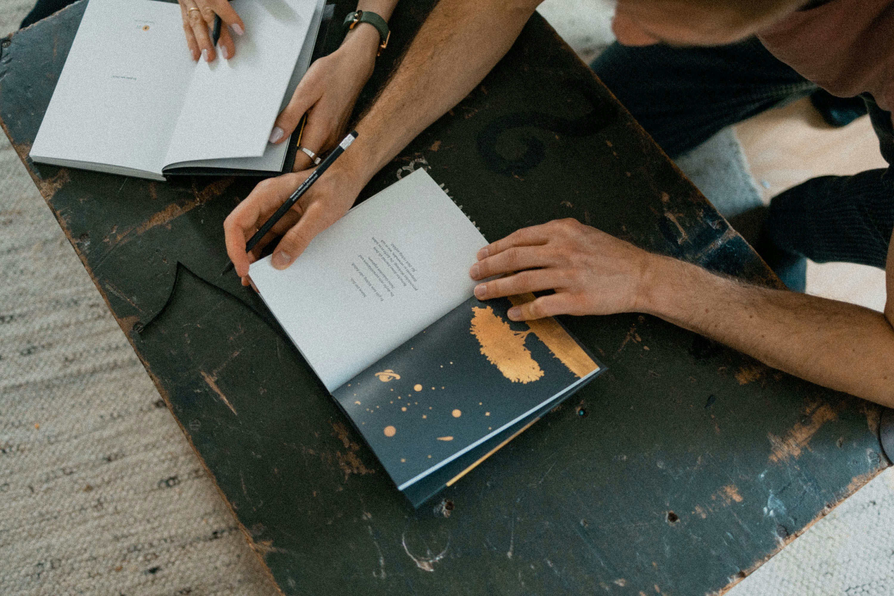 Two people collaborating on written documents at a dark work surface
