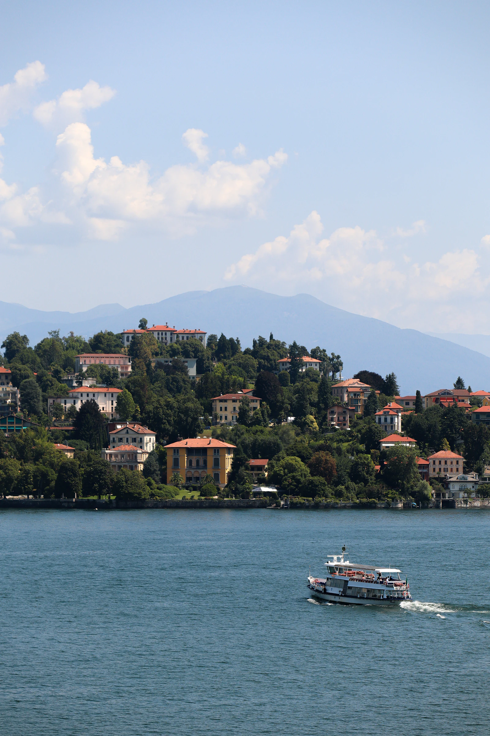 Boat on Lake Maggiore below green mountains