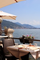 brown wooden table with chairs near body of water during daytime