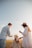 man and woman holding hands while walking on beach during daytime