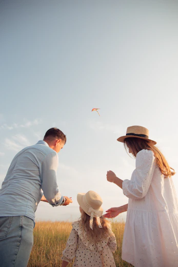 family flying kite in grassy field