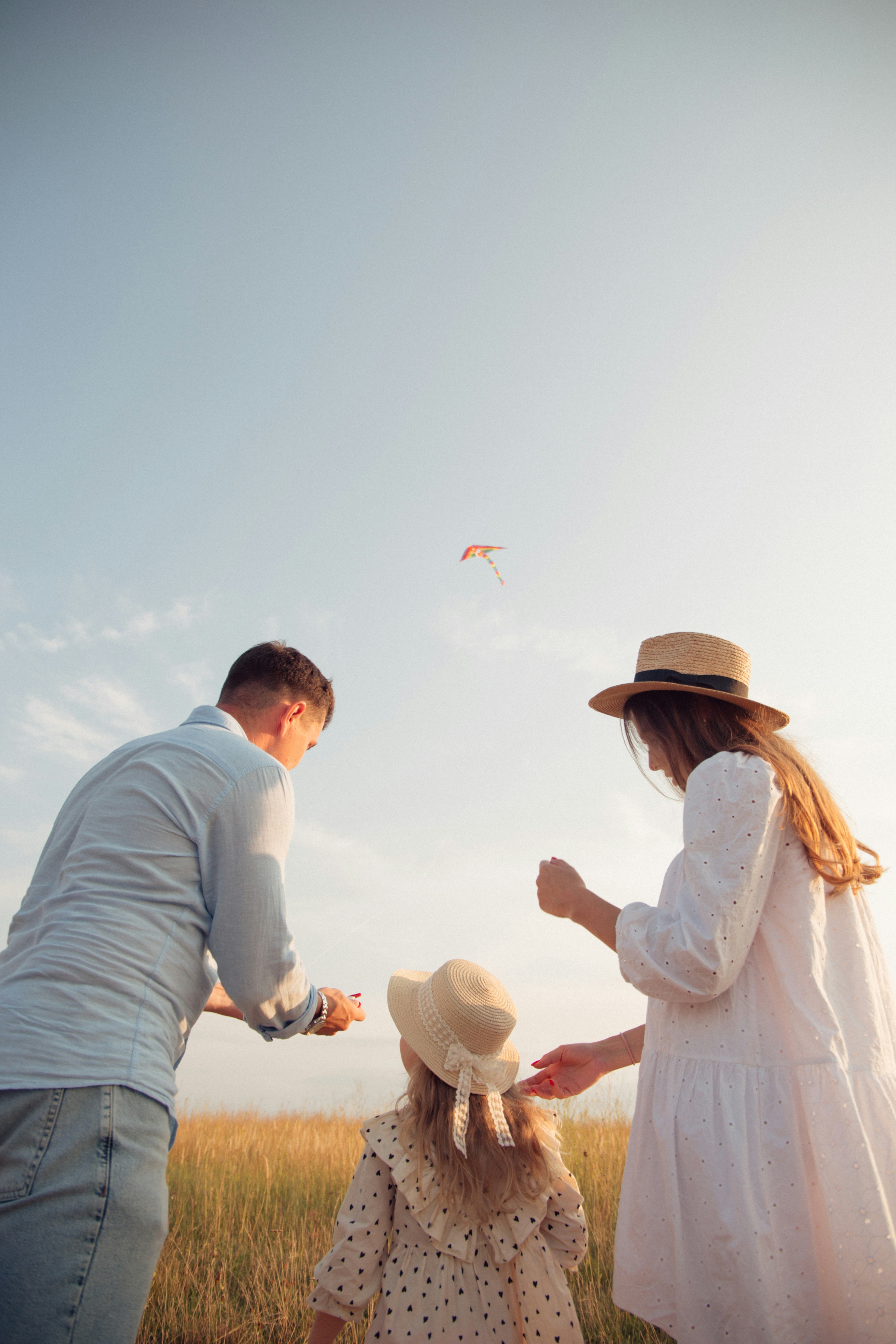 family flying kite in grassy field