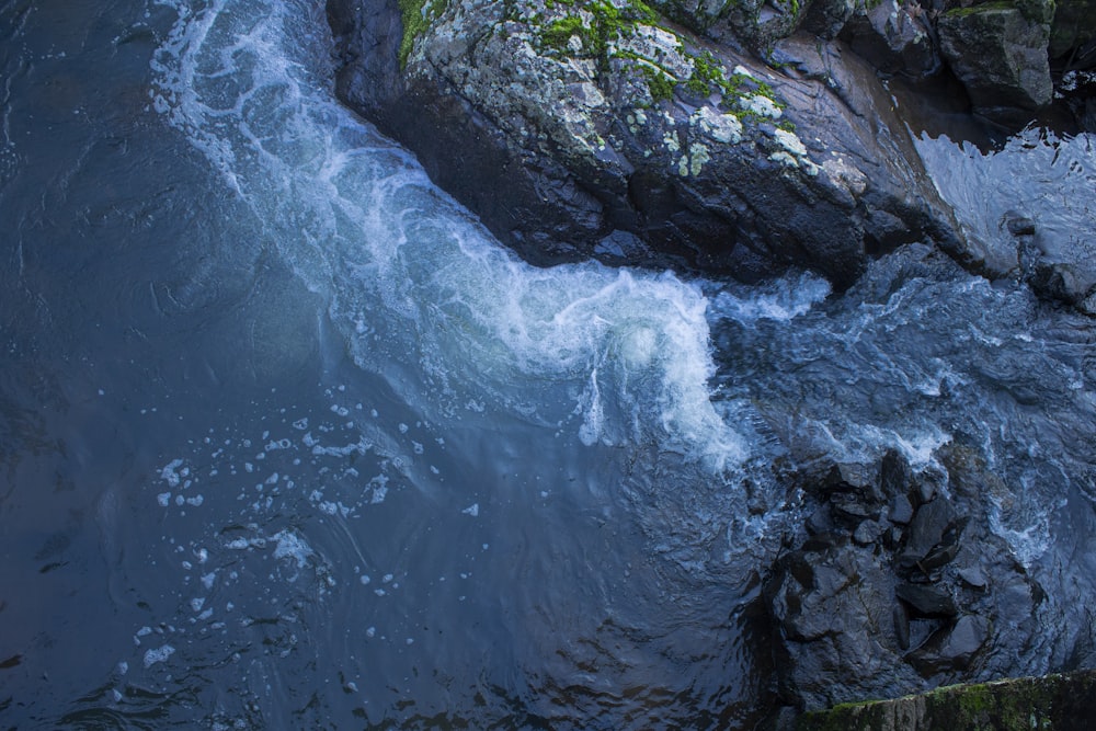 Le onde d'acqua colpiscono le rocce durante il giorno