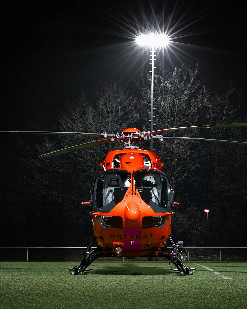 Helicóptero naranja y negro en campo de hierba verde durante la noche