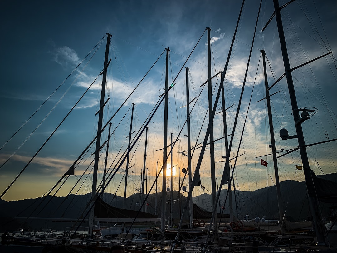 white sail boat on sea shore during sunset