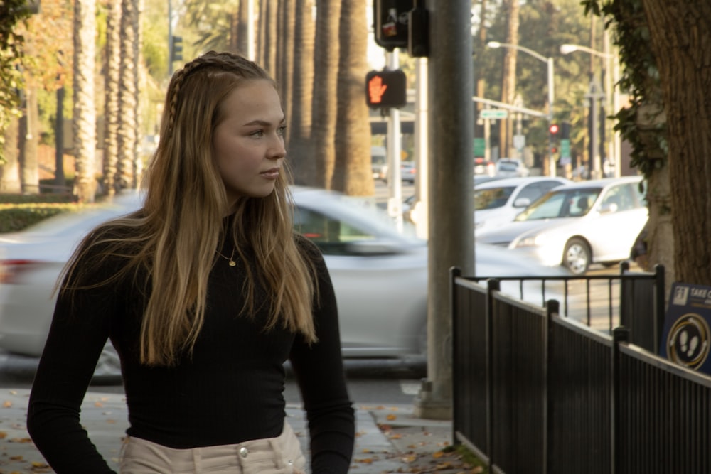 woman in black long sleeve shirt standing near white car during daytime