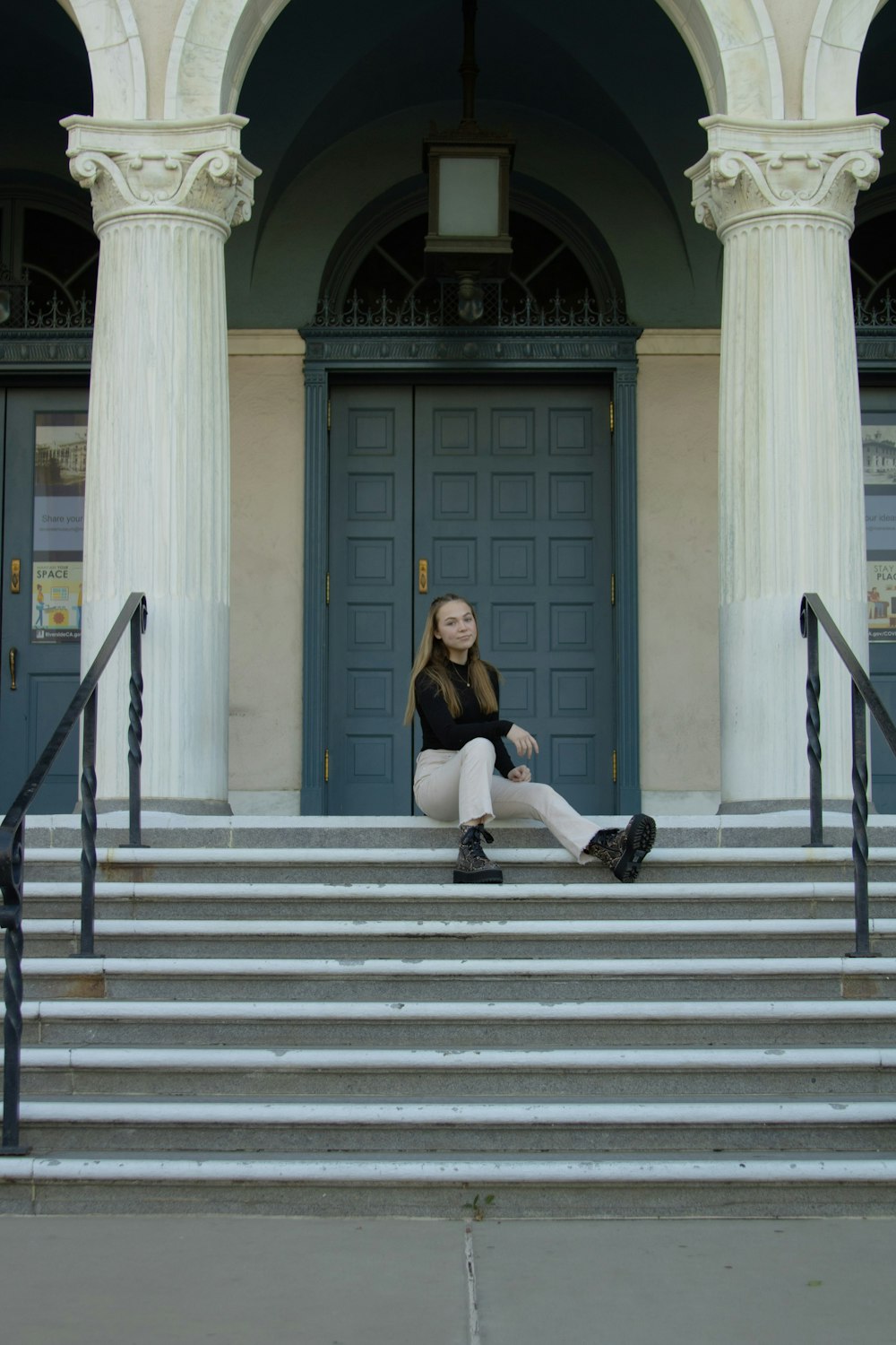 woman in black long sleeve shirt and black pants sitting on gray concrete staircase