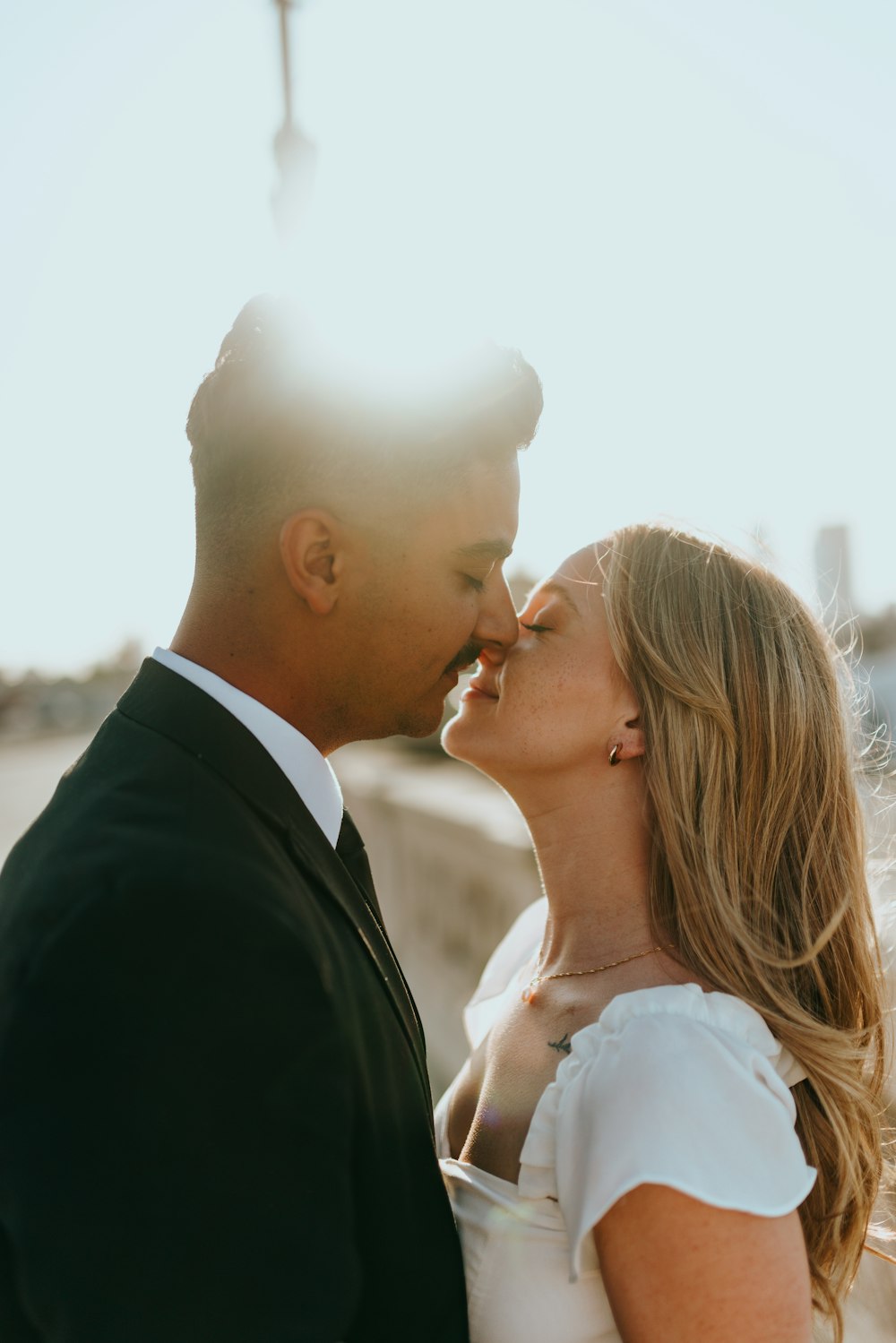 man in black suit kissing woman in white dress