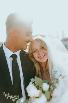 man in black suit kissing woman in white wedding dress