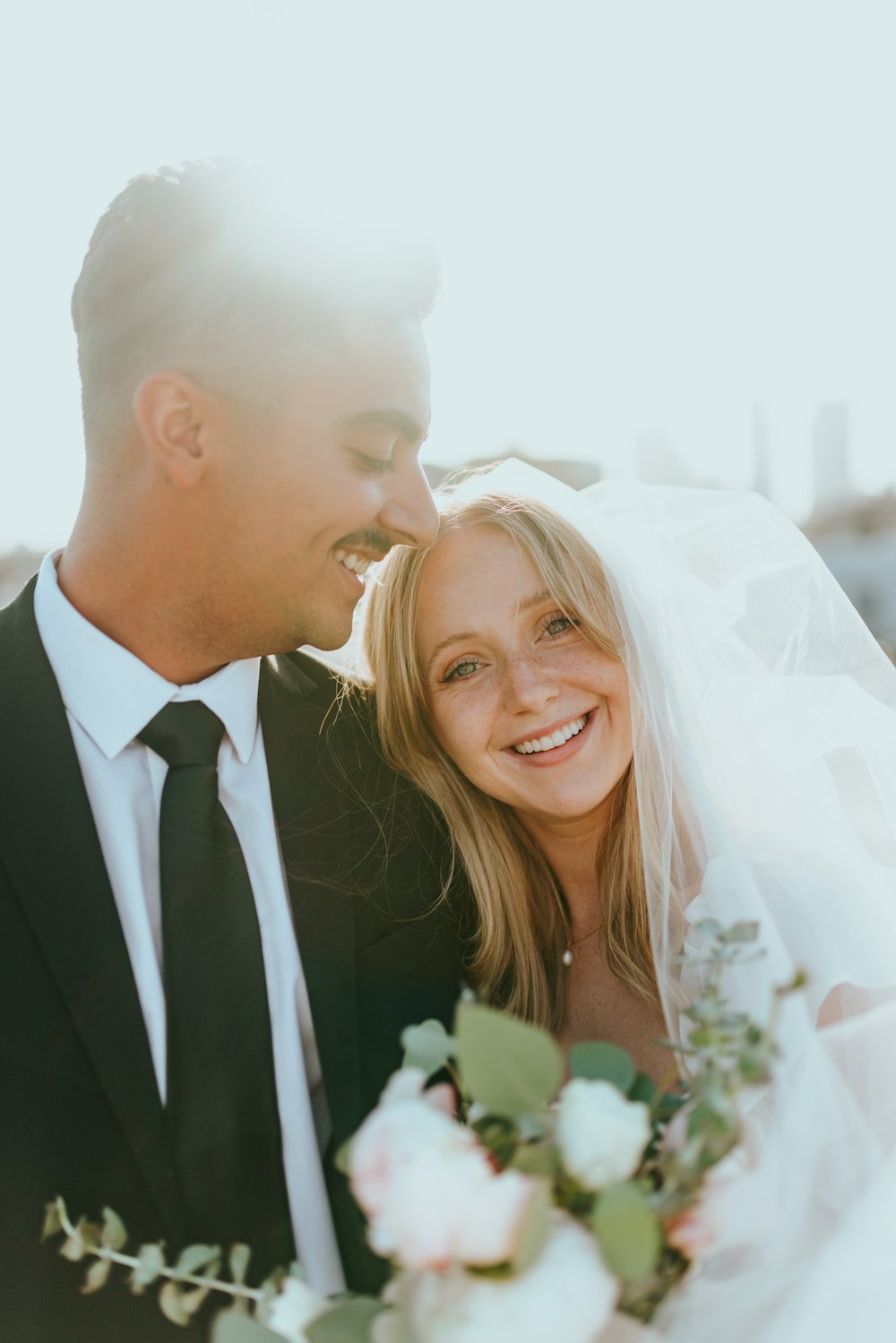 man in black suit kissing woman in white wedding dress