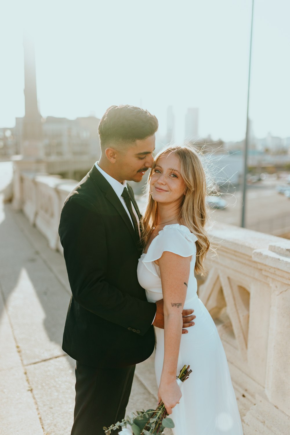 man in black suit hugging woman in white dress