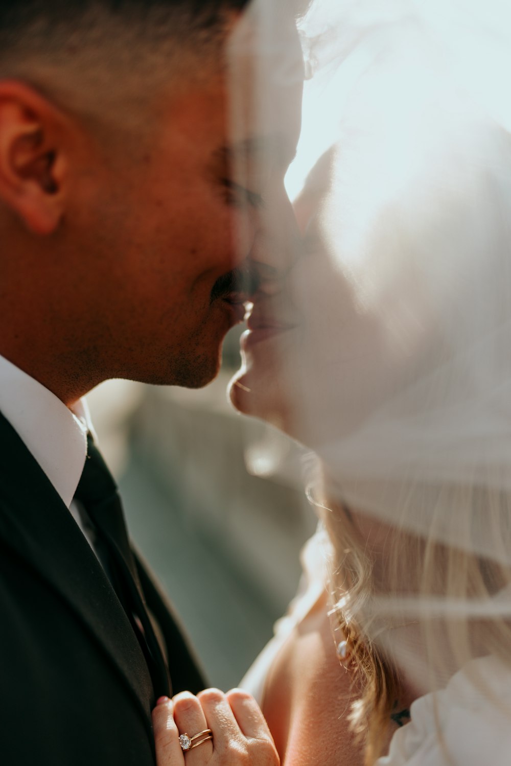 man in black suit jacket kissing woman in white wedding dress