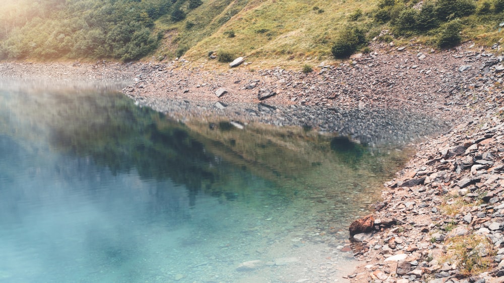 green and brown mountain beside body of water during daytime