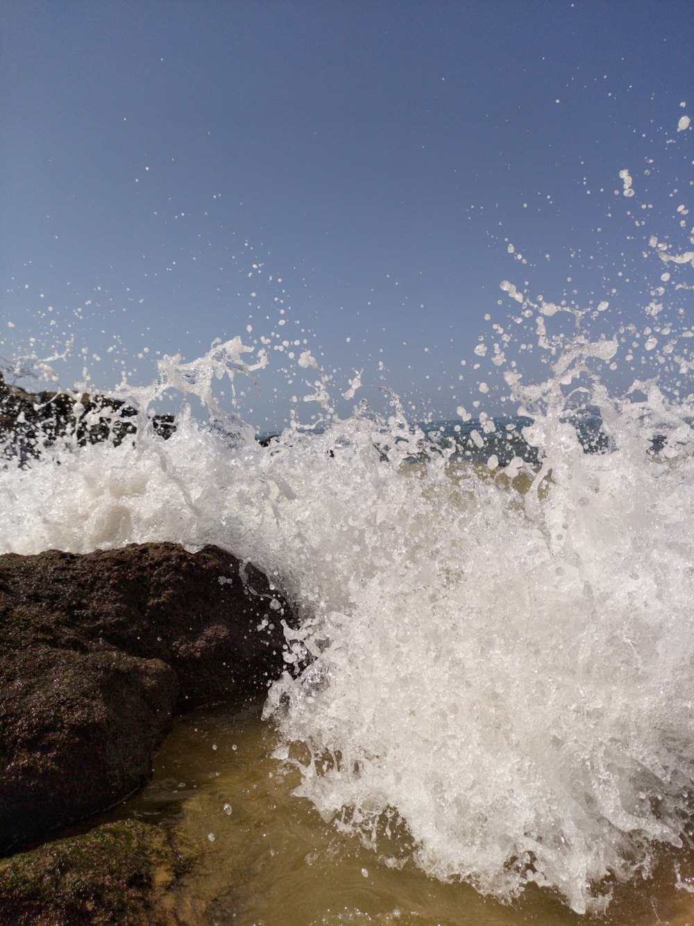 ocean waves crashing on brown rock during daytime