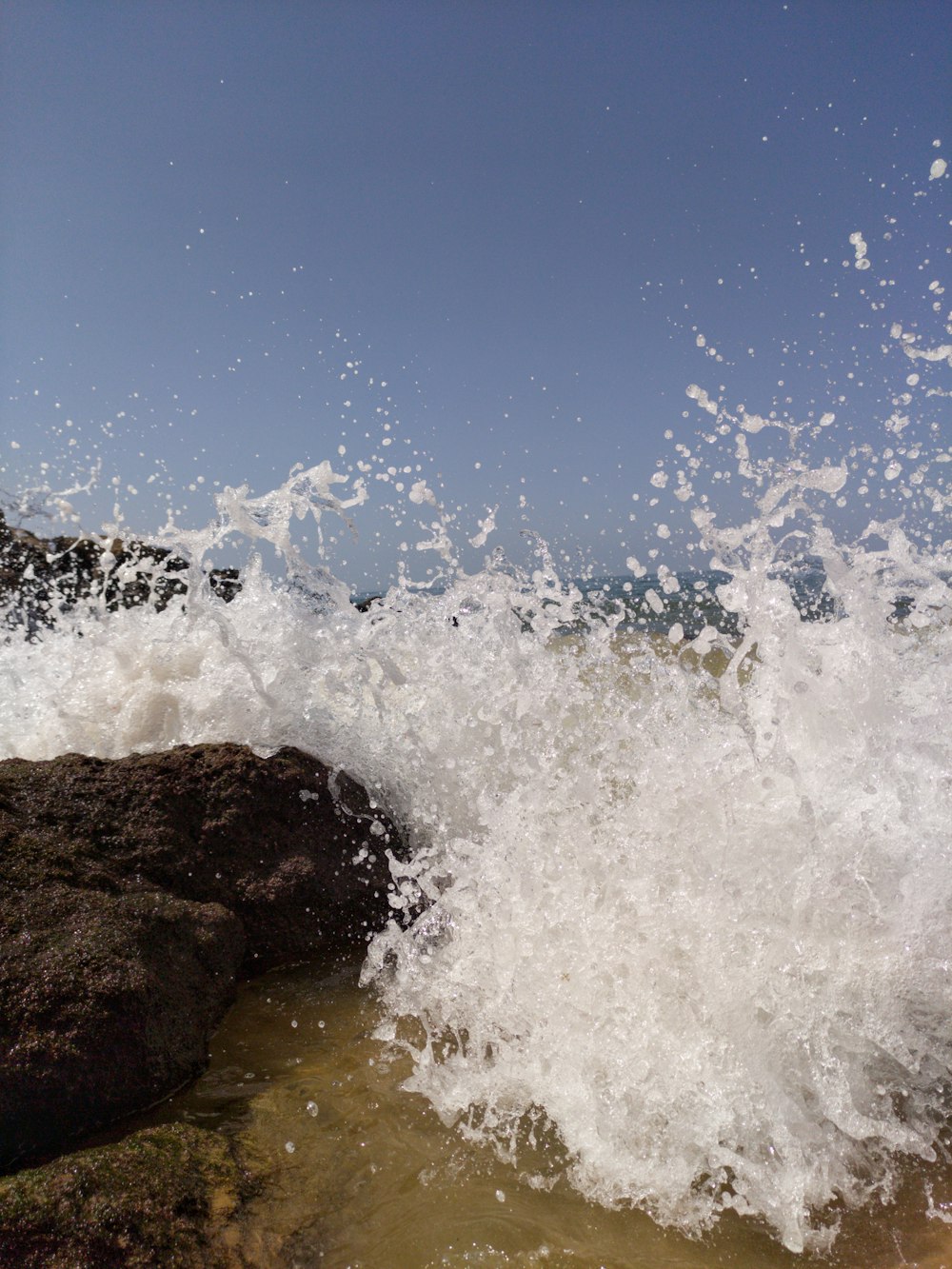 Olas del mar rompiendo contra Brown Rock durante el día