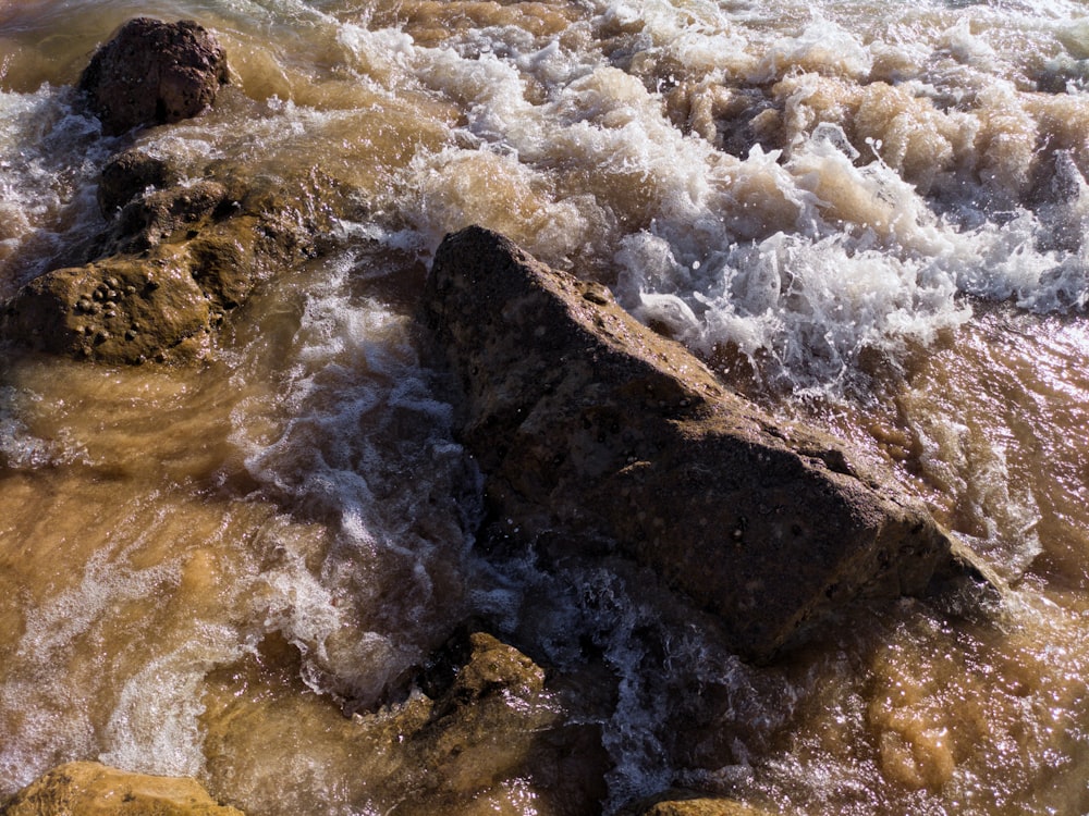 vagues d’eau frappant les roches brunes