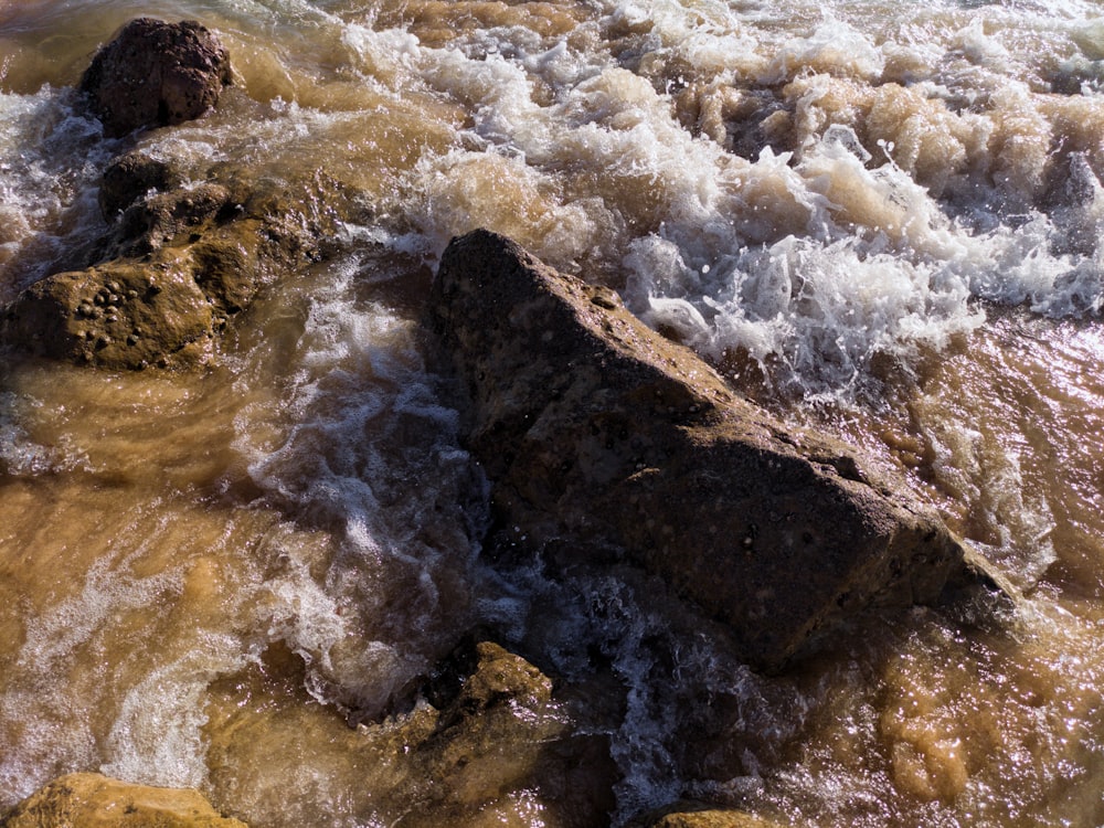 茶色の岩に当たる水の波