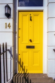 yellow wooden door with black steel door lever