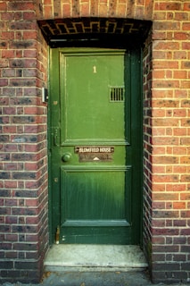 green wooden door on brown brick wall