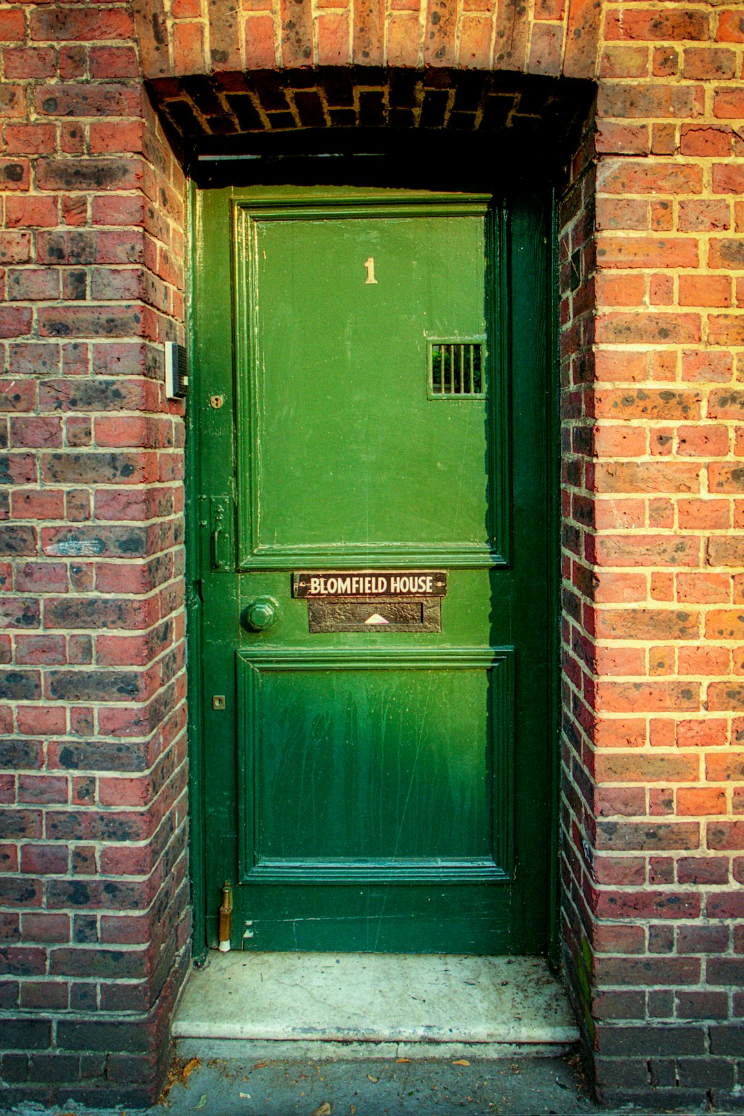 green wooden door on brown brick wall