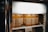 Several bottles of juice are neatly arranged on a shelf inside a refrigerator. The bottles have labels with Japanese writing, and the juice appears to be a light amber color. The refrigerator has a glass door allowing a clear view of the contents.