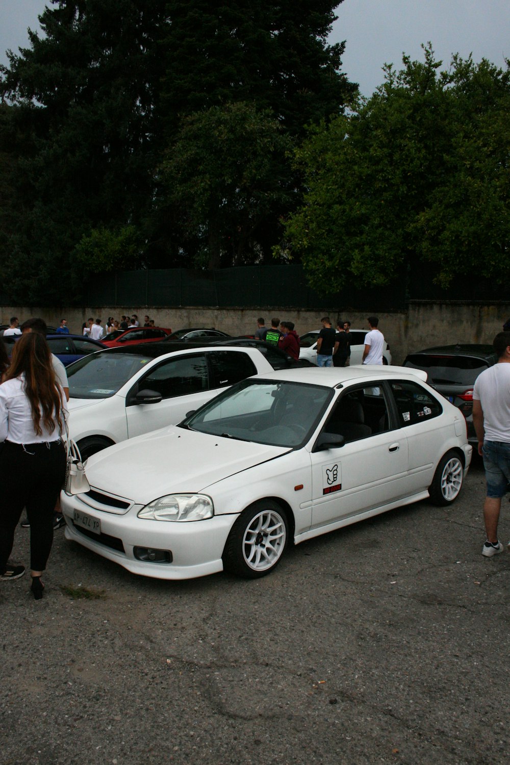 woman in white shirt standing beside white bmw m 3