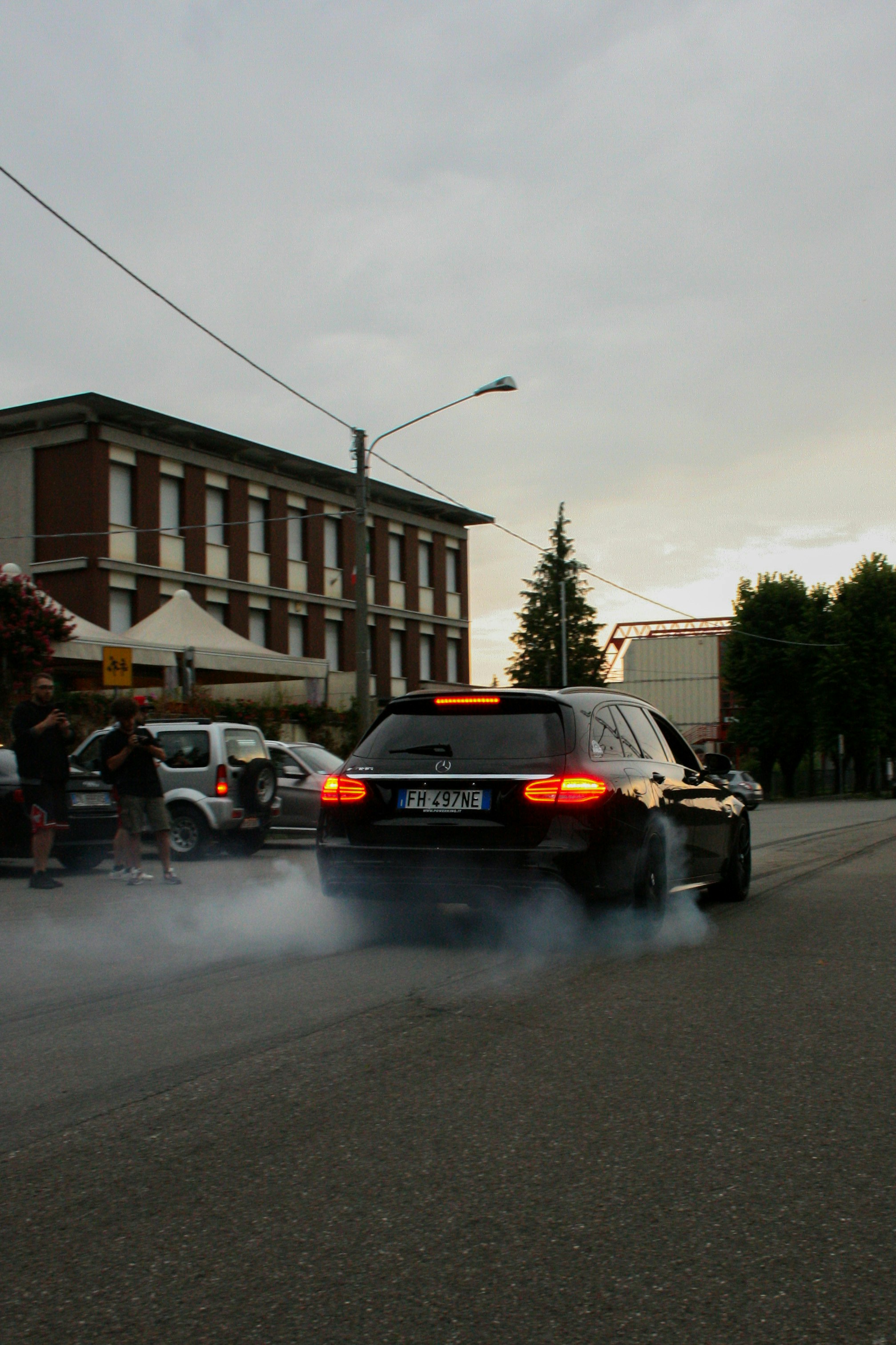 black car on road near people walking on sidewalk during daytime