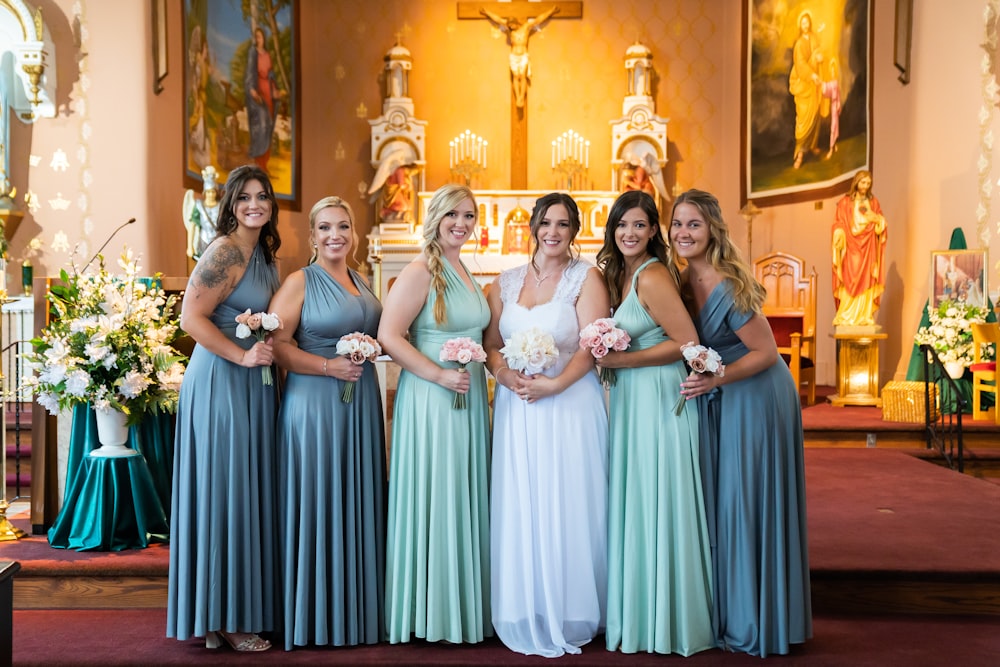 group of women wearing dresses standing on brown wooden floor