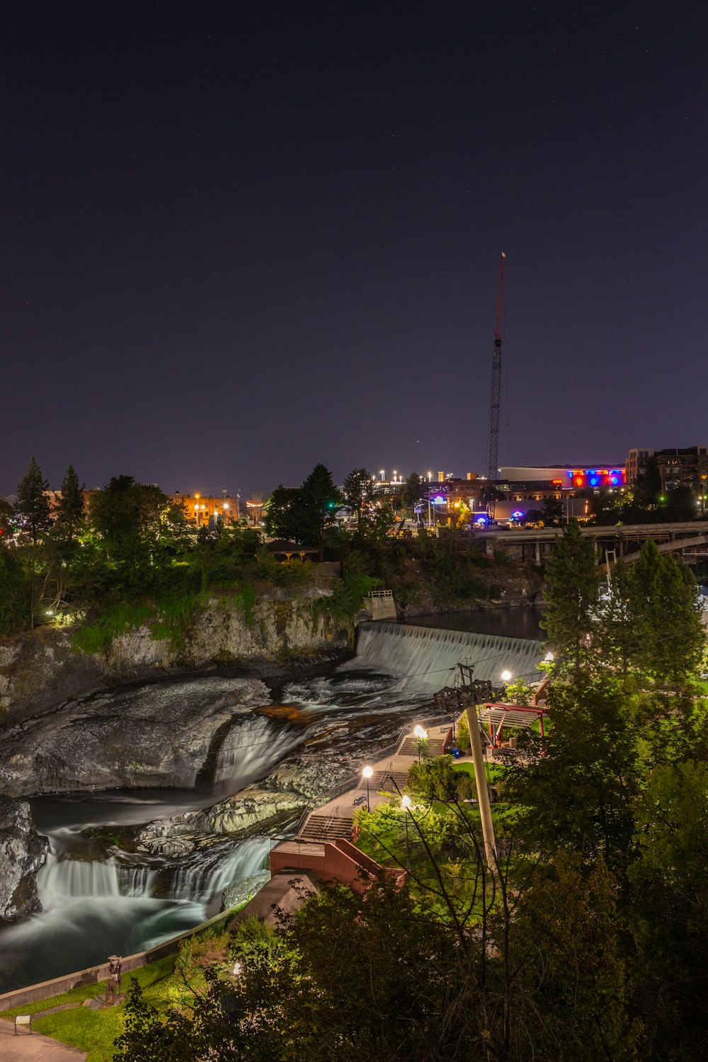 water falls near green trees during night time