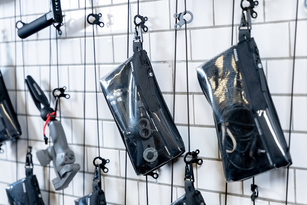 black leather sling bag hanging on white metal rack