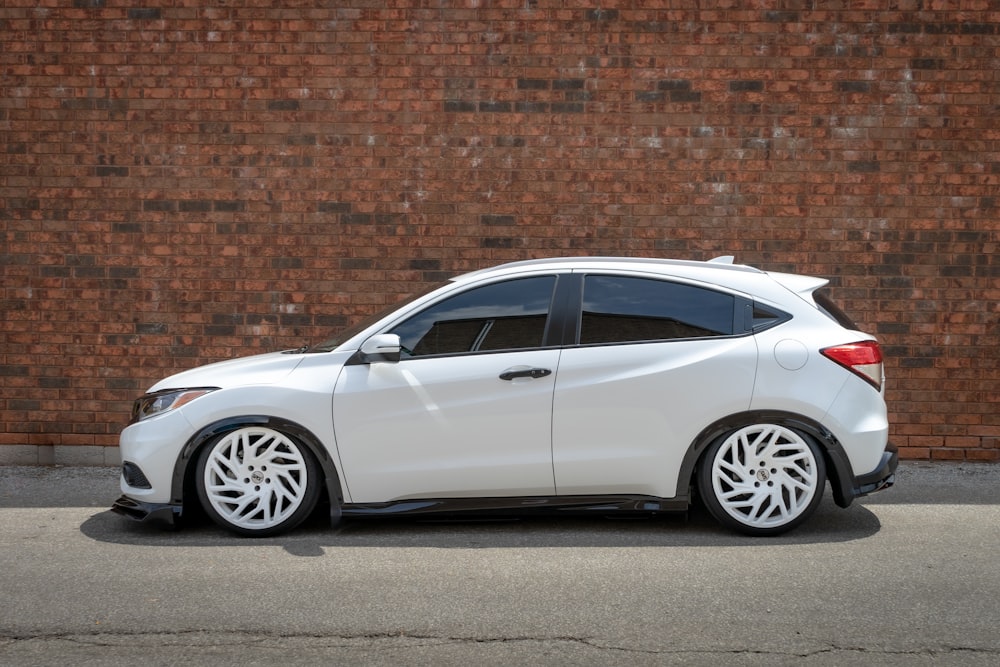 silver sedan parked beside brown brick wall